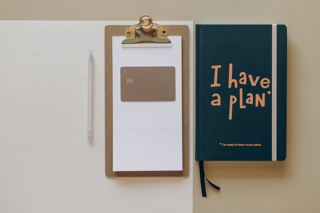 Home A minimalist office setup featuring a planner, clipboard, card, and pen, perfect for planning and organization.